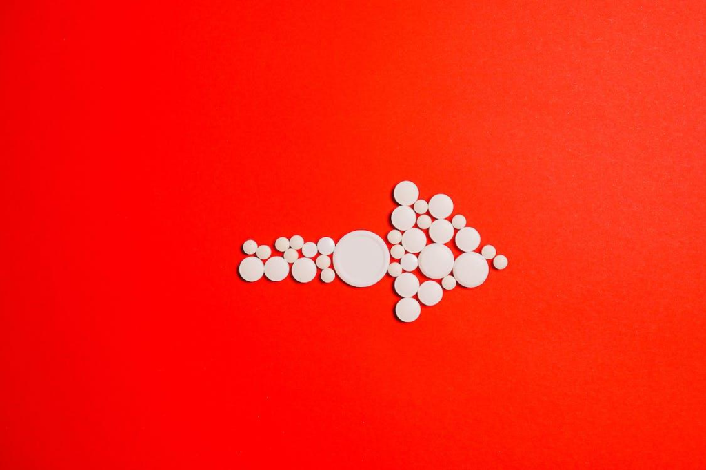 White tablets making an arrow on red surface